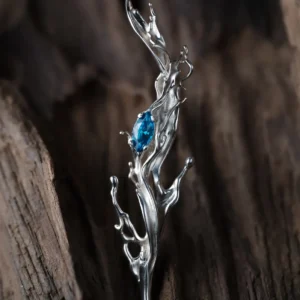 Tidewake Silver Earrings with fish-inspired sculptural design and marquise-cut blue gemstone; placed on wood surface, featuring flowing silver curves that evoke aquatic motion and handcrafted elegance in nature-themed Fish Earrings.