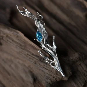 Tidewake Silver Earrings with fish-inspired flowing design and marquise-cut blue gemstone; placed on wood surface, featuring organic curves that evoke aquatic motion and handcrafted elegance in nature-themed Fish Earrings.