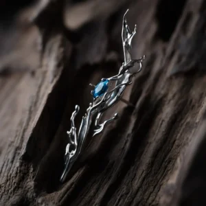 Tidewake Silver Earrings with fish-inspired sculptural design and blue gemstone; placed on wood surface, featuring organic flame-like curves and prong-set stone, highlighting aquatic elegance and handcrafted artistry in Fish Earrings.