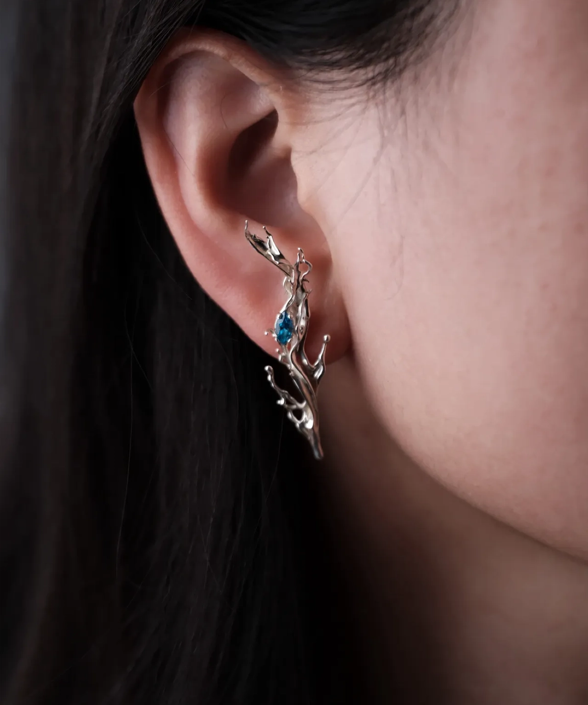 Tidewake Silver Earrings with fish-inspired sculptural design and blue gemstone; worn on ear, featuring organic branch-like curves that wrap elegantly, highlighting aquatic motion and handcrafted artistry in nature-themed Fish Earrings.