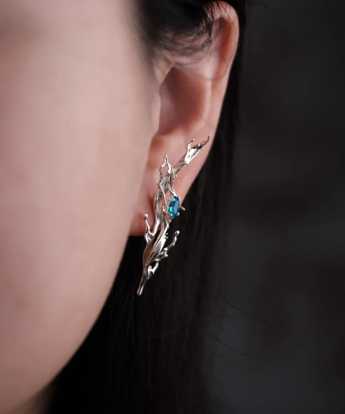 Tidewake Silver Earrings with fish-inspired flowing design and embedded blue gemstone; worn on ear, featuring organic flame-like curves that evoke aquatic motion and handcrafted elegance in nature-themed Fish Earrings.