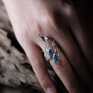 Sterling Silver Statement Ring with three marquise-cut blue gemstones and flowing fishtail-inspired silverwork; handcrafted ring worn on hand, styled against textured wood for natural contrast and artistic elegance.