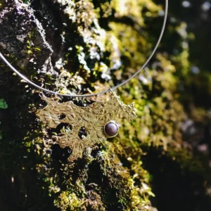 Tree Lichen Pendant on a silver choker necklace with natural agate; gold-toned organic pendant with embedded stone, styled against moss-covered rock to highlight forest-inspired craftsmanship and poetic botanical elegance.