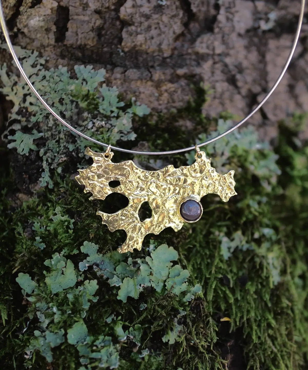 Tree Lichen Pendant on a silver choker necklace with natural agate; gold-toned organic pendant with embedded stone, styled against moss and bark to highlight forest-inspired craftsmanship and poetic botanical elegance.