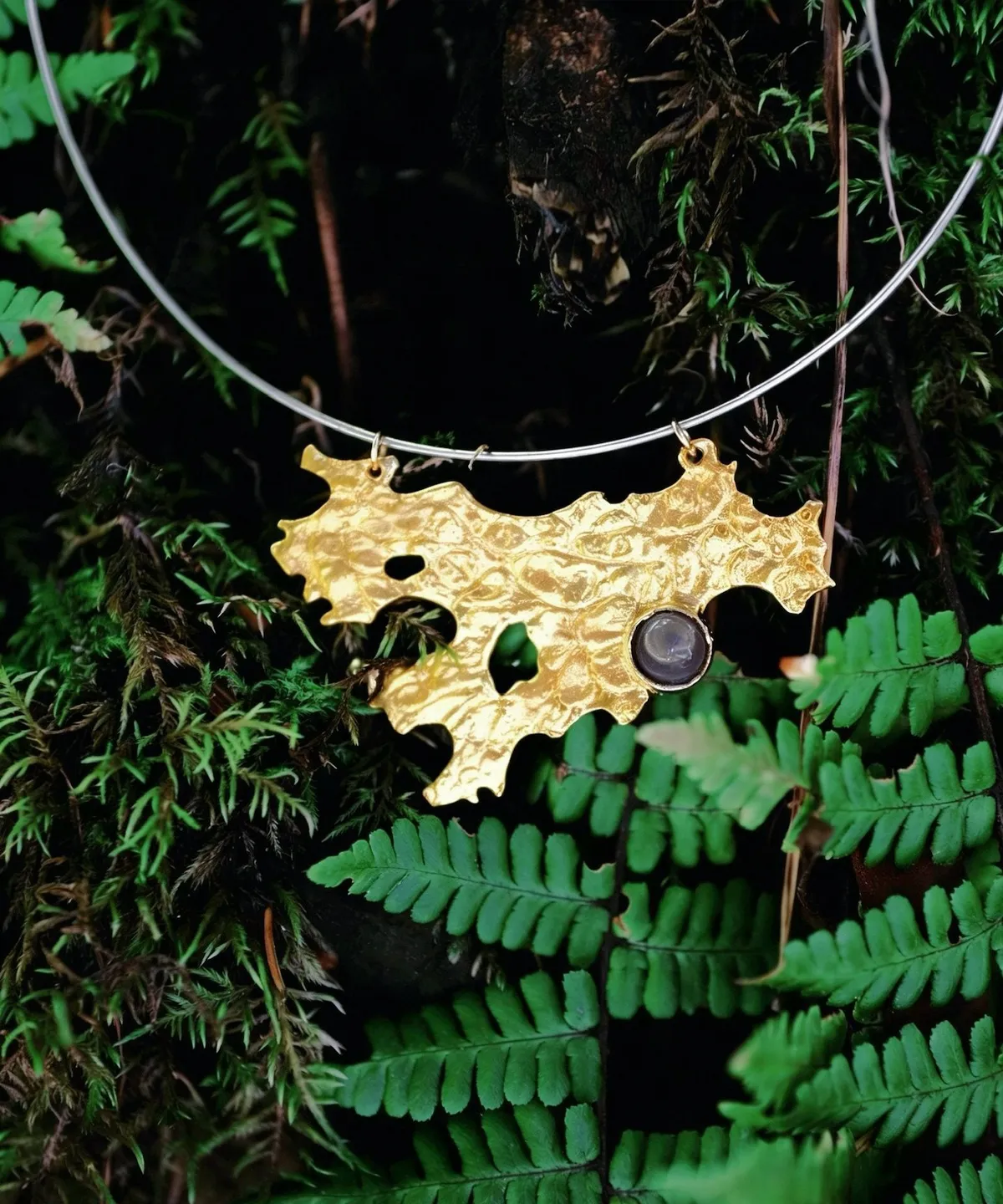 Tree Lichen Pendant on a silver choker necklace with natural agate; gold-toned organic pendant with embedded stone, styled against moss and fern backdrop to highlight forest-inspired craftsmanship and botanical elegance.