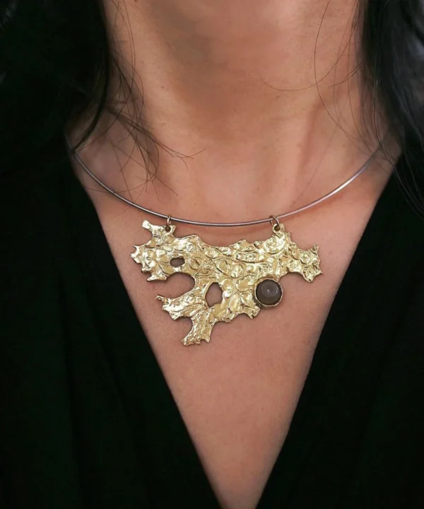 New In 31 Tree Lichen Pendant on a silver choker necklace with natural agate; worn over black fabric to highlight the gold-toned organic pendant with embedded stone, showcasing forest-inspired elegance and handcrafted detail.