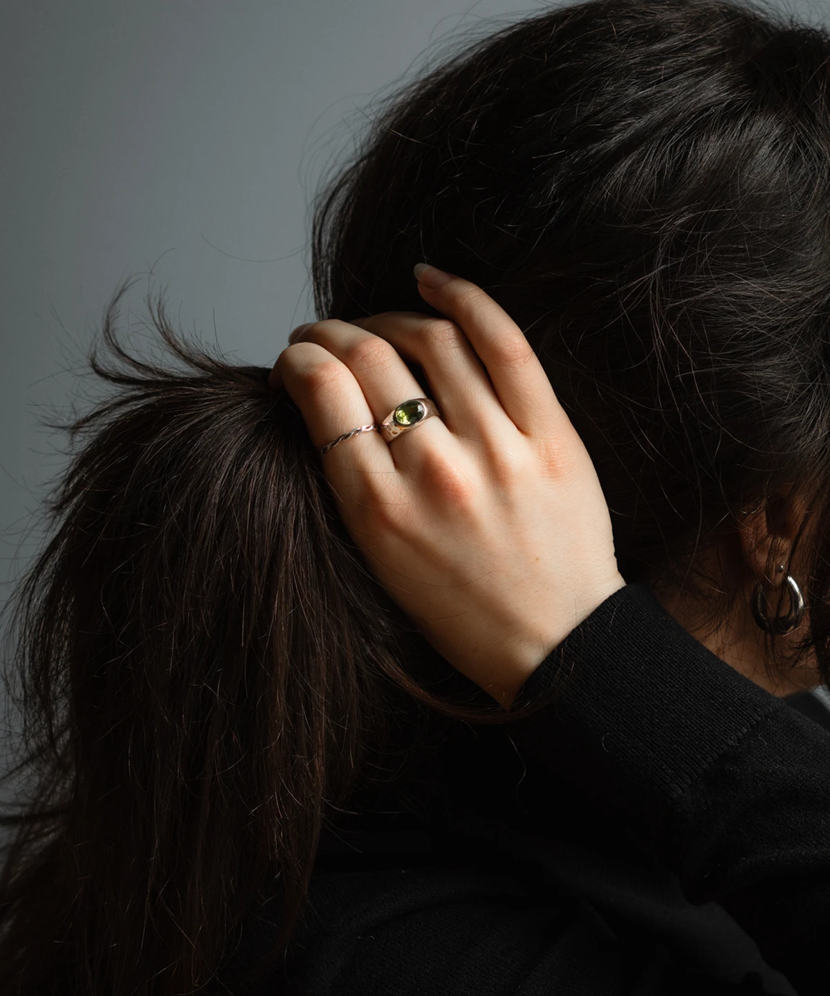 August Birthstone Ring-Natural Peridot Ring in Sterling Silver 09 Hand wearing a silver August Birthstone Ring with a green gemstone, shown against dark clothing and hair to highlight the Natural Peridot Ring design.
