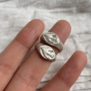 Flying Bird Ring-Handmade 999 Silver Signet Pinky Ring 06 Two silver Signet Pinky Rings with sculpted hand motifs worn on adjacent fingers, shown against soft textured white fabric.