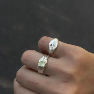 Flying Bird Ring-Handmade 999 Silver Signet Pinky Ring 08 Hand wearing two silver Signet Pinky Rings with sculpted hand motifs, shown against soft white textured fabric.