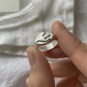 Flying Bird Ring-Handmade 999 Silver Signet Pinky Ring 11 Hand holding a silver Signet Pinky Ring with a raised hand motif, shown against soft white fabric with focus on the ring’s sculptural detail.