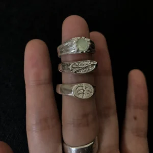 Handmade 999 Silver Gemstone Ring with Natural Prehnite 09 Hand wearing stacked Silver Gemstone Rings, including a Natural Prehnite Ring with a pale green stone, shown against a dark background to highlight the jewelry details.
