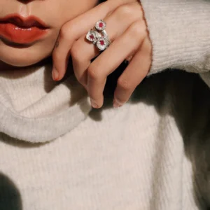 A handcrafted Poppy‑Inspired Ruby Ring in S925 sterling silver worn on the hand, featuring three red gemstone bezels and a textured organic design against a soft, neutral background.