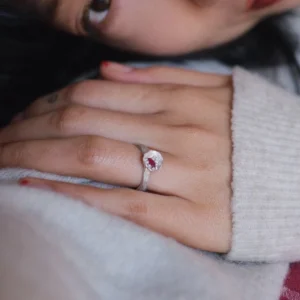 Poppy-Inspired Ruby Ring in S925 Sterling Silver 04 A handcrafted Poppy‑Inspired Ruby Ring in S925 sterling silver worn on the hand, featuring a red gemstone in a round bezel setting in a soft, intimate close‑up composition.
