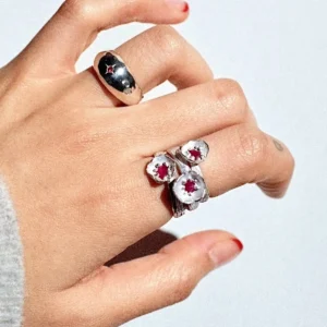 A handcrafted Poppy‑Inspired Ruby Ring in S925 sterling silver worn on the hand, featuring red gemstone floral details and a bold stacked design in a close‑up composition.