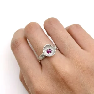 Poppy-Inspired Ruby Ring in S925 Sterling Silver 11 A handcrafted Poppy‑Inspired Ruby Ring in S925 sterling silver worn on the finger, featuring a faceted ruby center stone and textured organic metalwork in a close‑up hand shot.