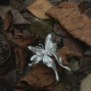 A handcrafted S990 Sterling Silver Butterfly Ring resting on dried leaves and soil, featuring detailed wings and a sculpted form that highlights its organic, nature‑inspired design.