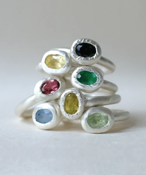 Stack of handmade S925 sterling silver rings with multi-color natural tourmaline gemstones, displayed on a light neutral background, part of a tourmaline ring collection