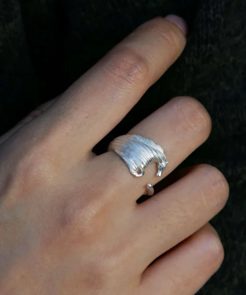 Close-up of a hand wearing a handmade 925 sterling silver Horse Ring Jewelry with a textured horse head design, against a dark fabric background.