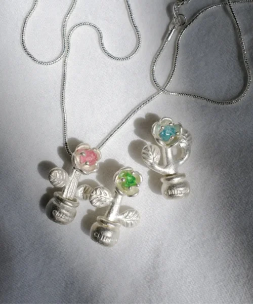 Three S925 Sterling Silver Potted Flower Tourmaline Necklace pendants with pink, green, and blue tourmaline, displayed on white linen fabric