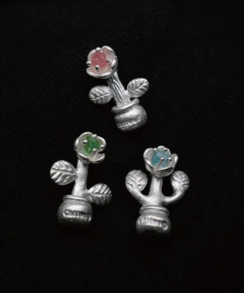 Three S925 sterling silver potted flower charms with pink, green, and blue gemstone centers displayed on a dark textured background, styled to complement the natural elegance of a Tourmaline Necklace design.