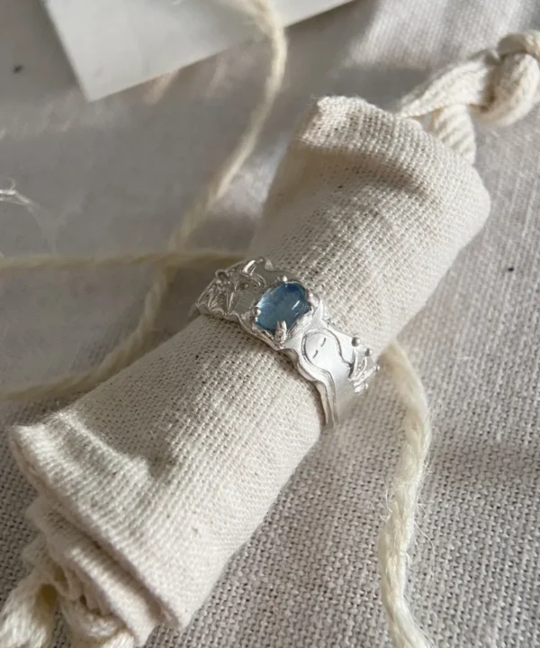A handmade Aquamarine Ring in 999 fine silver, featuring a natural light blue aquamarine gemstone, displayed on a linen jewelry roll with soft natural light.