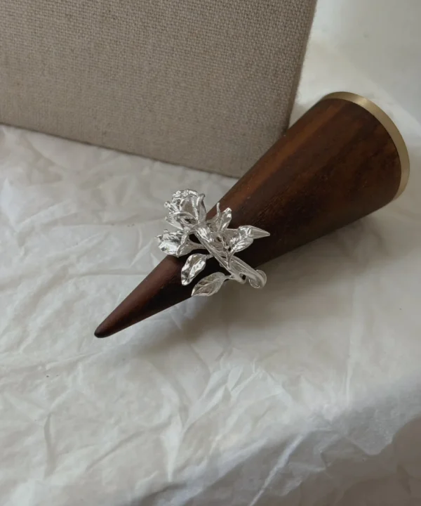 New In 10 Handmade S925 sterling silver Rose Ring with detailed rose bloom and leaf design, displayed on a wooden ring cone against a linen background.