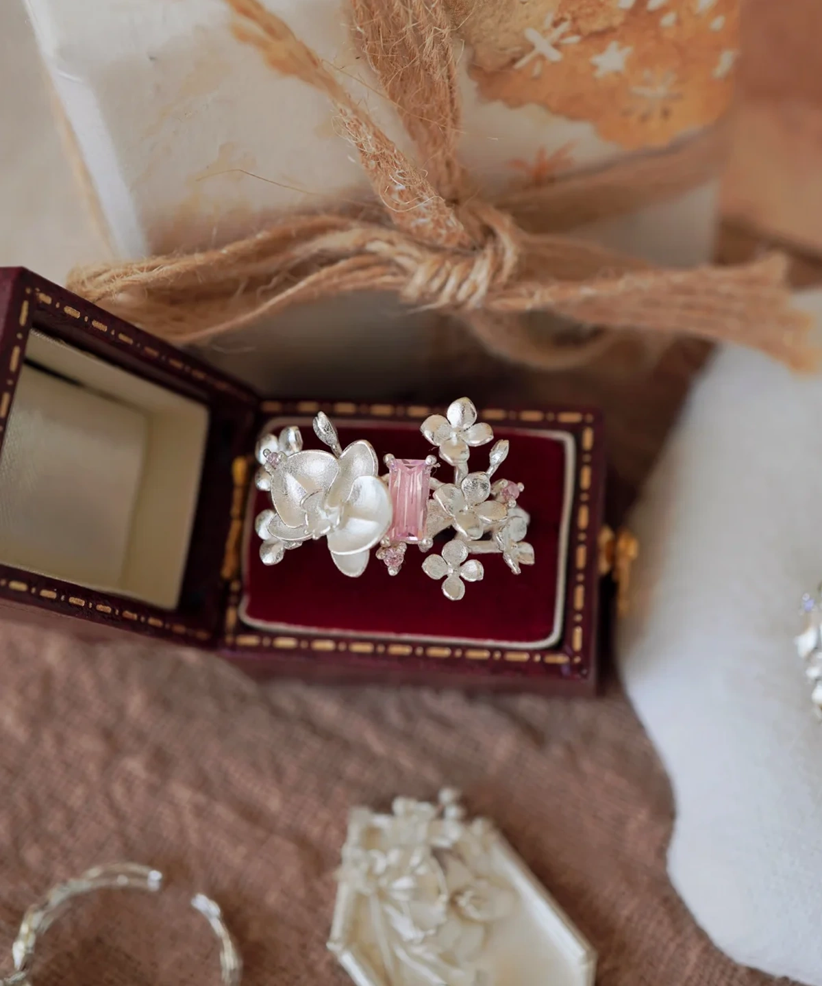 A Unique Gemstone Ring in S925 silver, orchid-inspired design with a central pink rectangular-cut gemstone, presented in a vintage-style box.