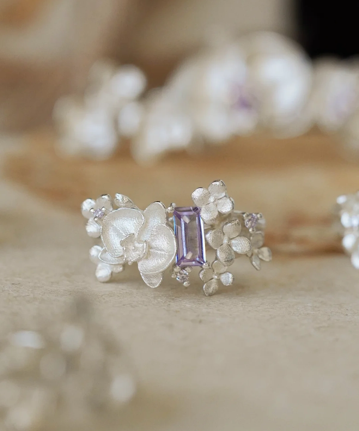 Close-up of the Unique Gemstone Ring, an orchid-inspired S925 silver ring with a central purple rectangular-cut gemstone.