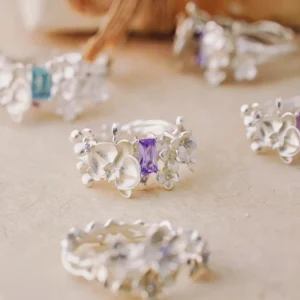 A close-up of the Unique Gemstone Ring, an orchid-inspired S925 silver ring with a central purple gemstone and delicate floral details.