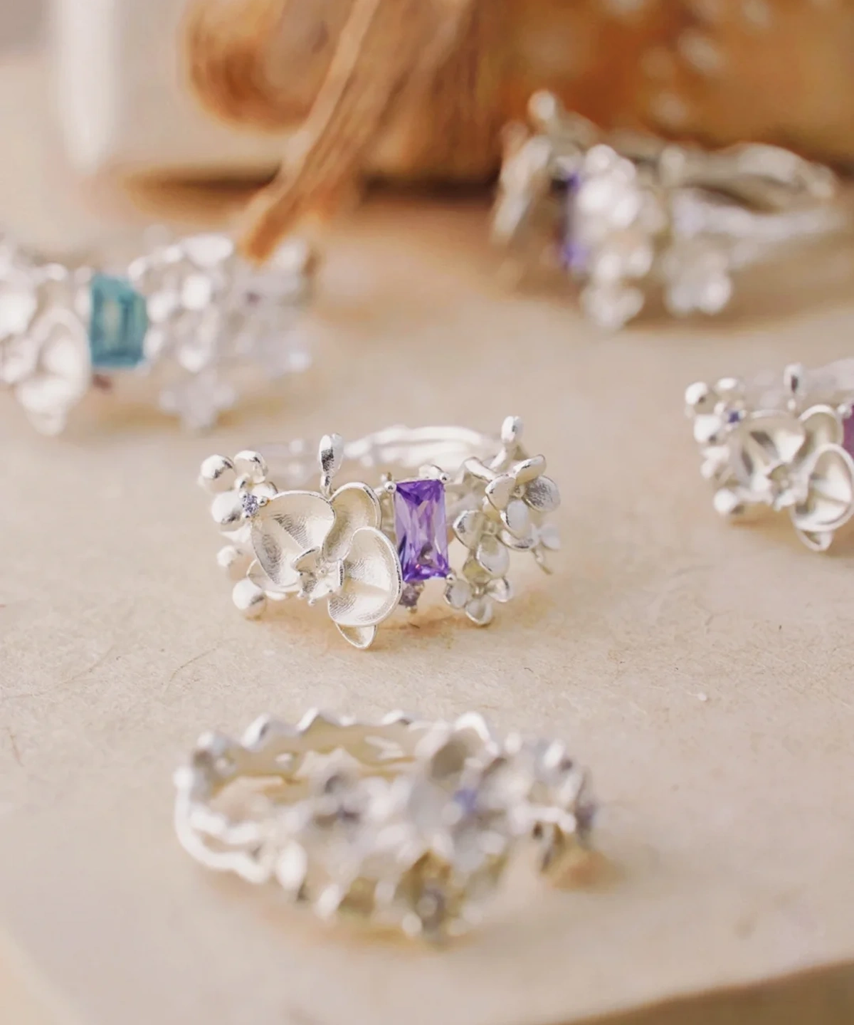 A close-up of the Unique Gemstone Ring, an orchid-inspired S925 silver ring with a central purple gemstone and delicate floral details.
