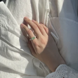 A hand wearing a Custom Couple Ring in S925 silver, featuring a natural light green tourmaline gemstone in an organic setting.