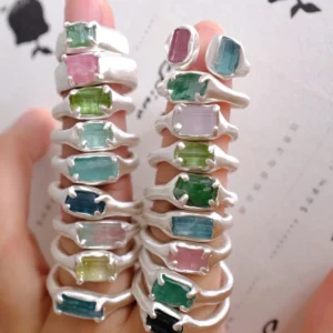 Close-up of stacked Custom Couple Rings in S925 silver, featuring natural multi-color tourmaline gemstones with organic handcrafted settings, held in fingers.