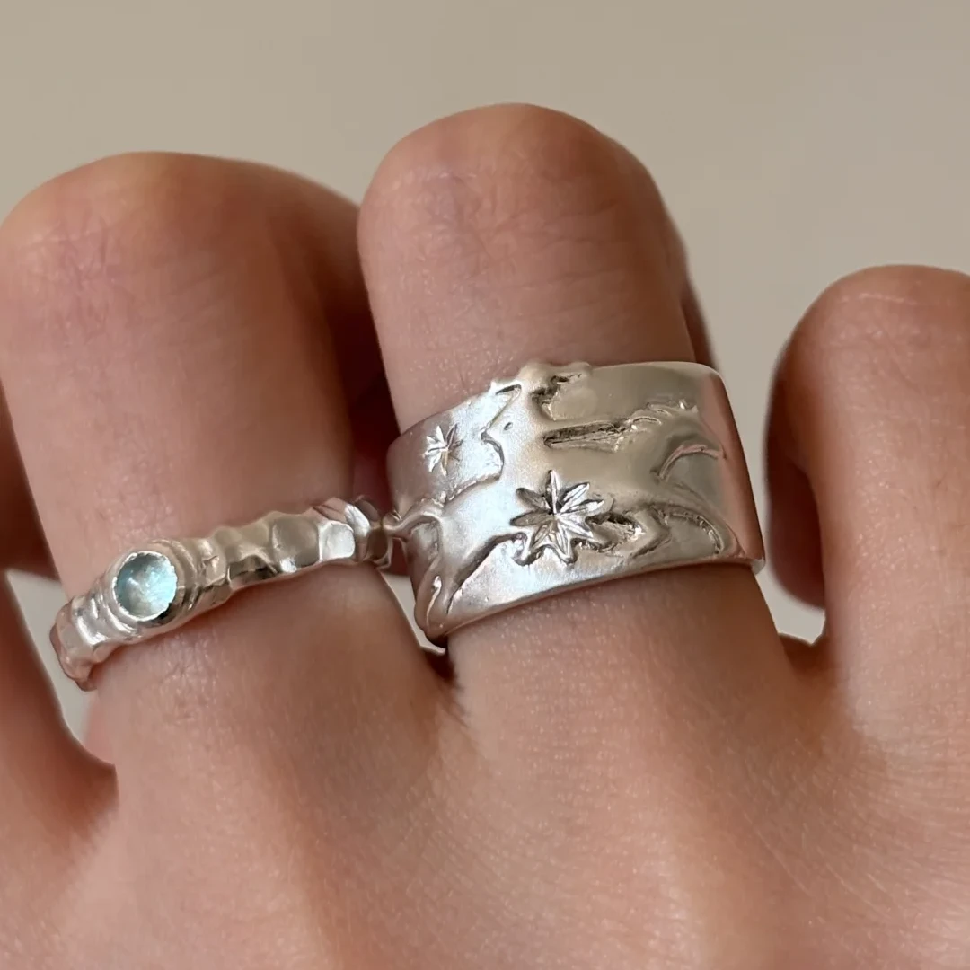 999 fine silver horse ring worn on the hand, with carved star and flowing line details on a wide silver band.