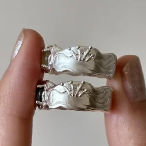Two 999 silver rings showing carved mushroom and starburst motifs on back of band