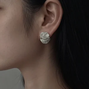 close up of silver stud earrings on ear, matte brushed finish, handmade detail
