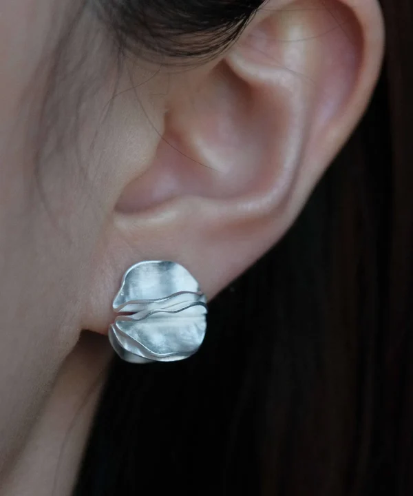 handmade sterling silver stud earrings worn on ear, sculptural round silver earring close up
