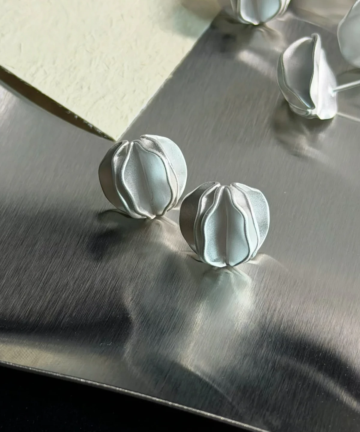 Sterling Silver Stud Earrings – Styled Display with Florals multiple sterling silver stud earrings on metal surface with flowers, handmade jewelry display