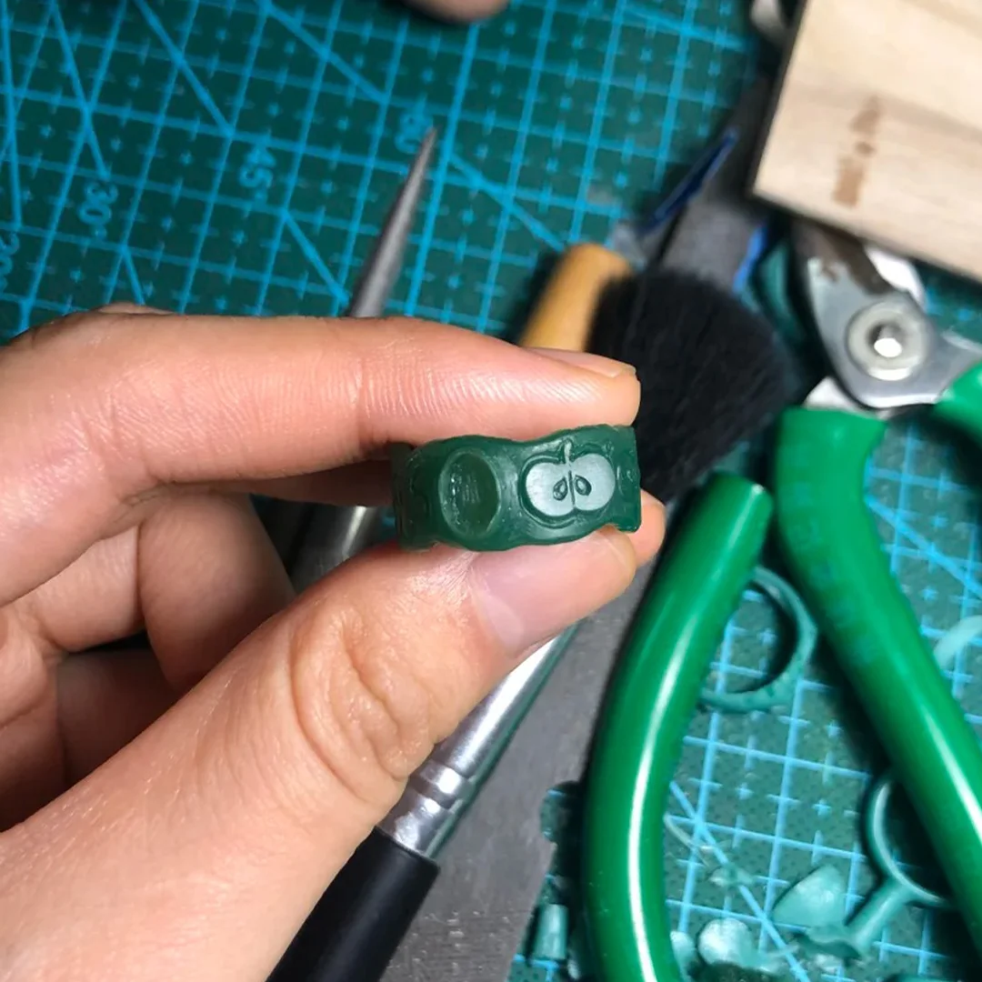 Green wax carving for an apple ring, showing the small hand-carved form before it is cast into silver.