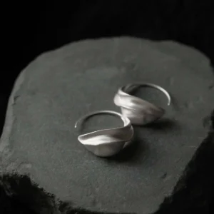 silver crescent moon earrings pair on dark slate, moody lighting showing silver hoop detail