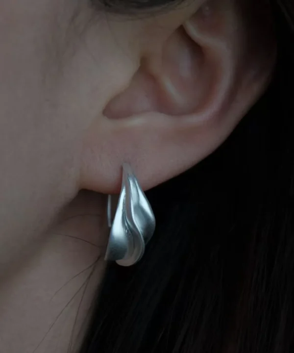 sterling silver crescent moon earrings close up on ear, showing sculpted curve and silver finish