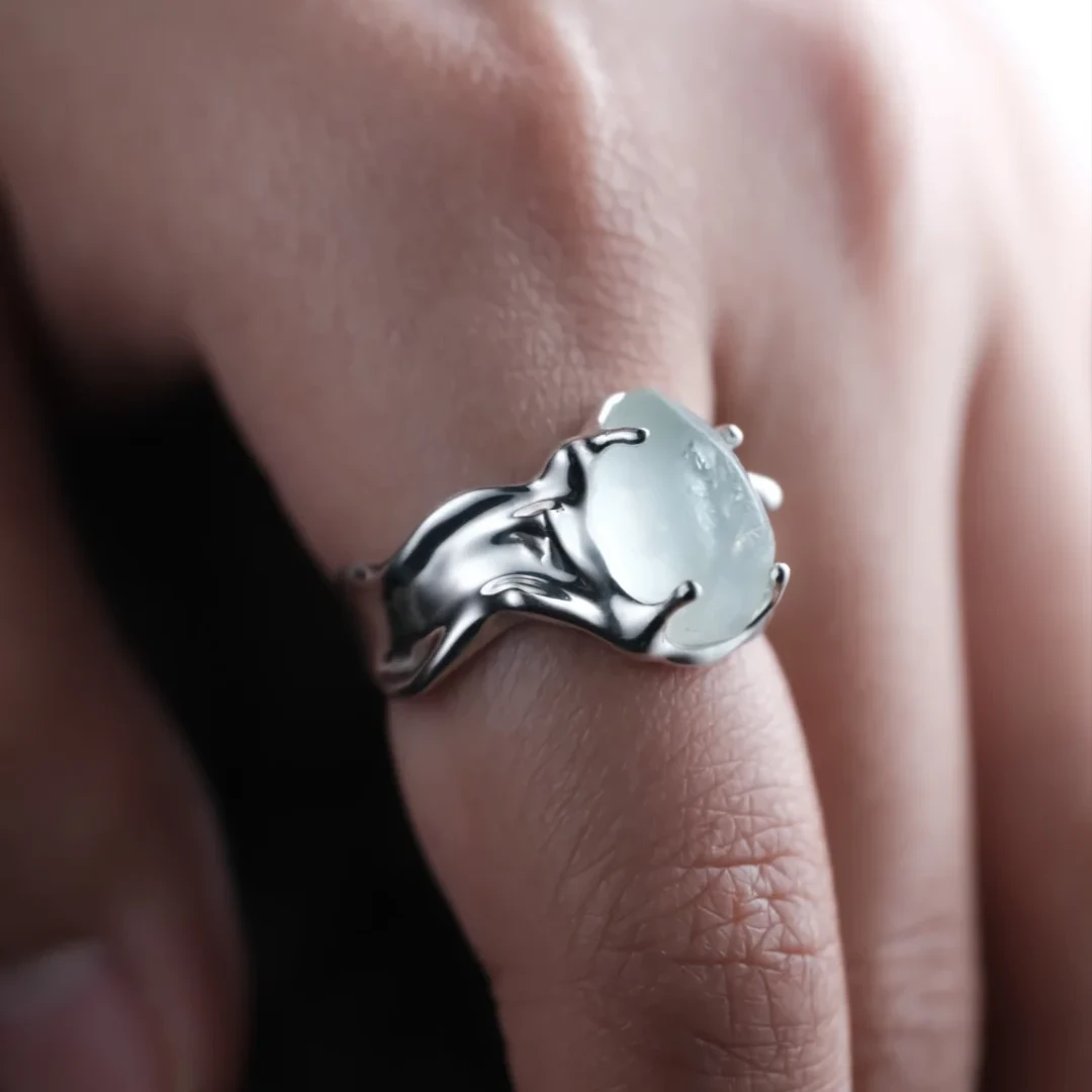 Freeform aquamarine silver ring worn on the hand, with organic silver curves shaped around the natural stone.
