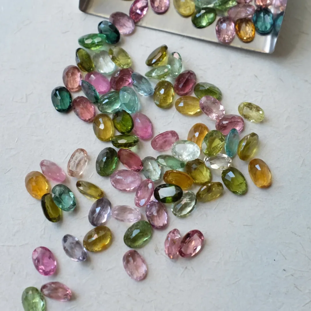 Loose natural tourmaline gemstones in soft pink, green, yellow, and blue tones, selected for artisan jewelry designs.