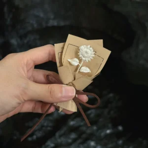silver sunflower gift single stem in kraft paper, sterling silver flower against dark rock