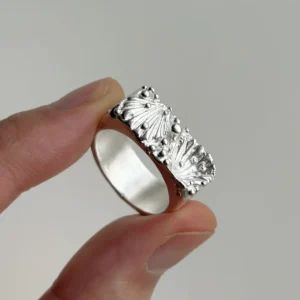 wide silver band ring with two shell forms and silver granules on the face, 999 fine silver, hand-held