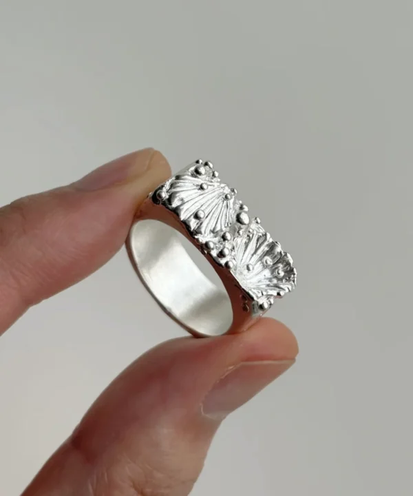 wide silver band ring with two shell forms and silver granules on the face, 999 fine silver, hand-held