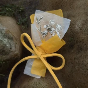 5.5 g miniature 950 silver iris bouquet in warm wrapping resting on a wet stone