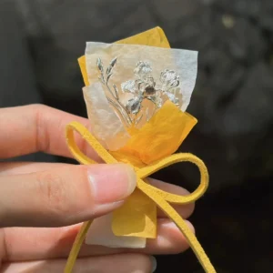 Hand holding a 5.5 g miniature iris bouquet in 950 silver with warm wrapping