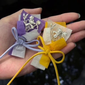 Two 5.5 g miniature 950 silver iris bouquets in purple and warm wrapping held in one hand
