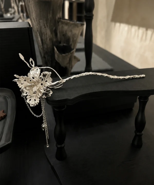 950 silver iris flower hair stick with a long textured stem and hanging chains displayed on black