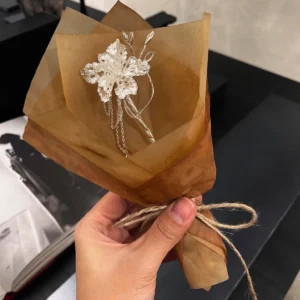 Iris flower hair stick in 950 silver presented by hand as a small bouquet in brown paper